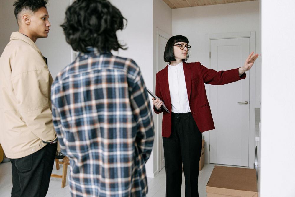 A couple being walked through a rental unit by a person in a blazer