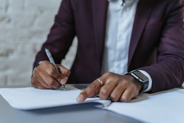 a-person-in-a-dark-suit-signing-a-document